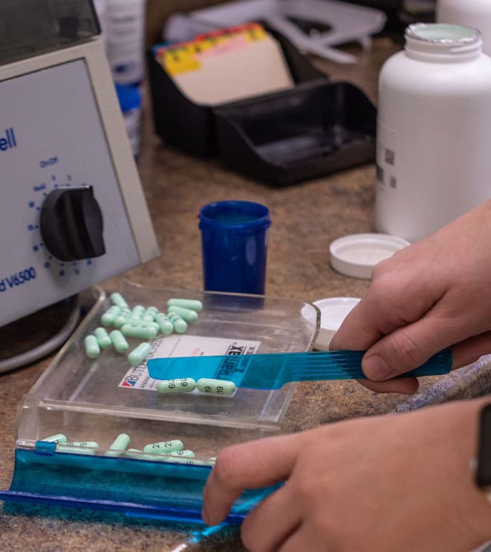 Grand Valley Animal Hospital employee measures out exact doses of medicine for a patient