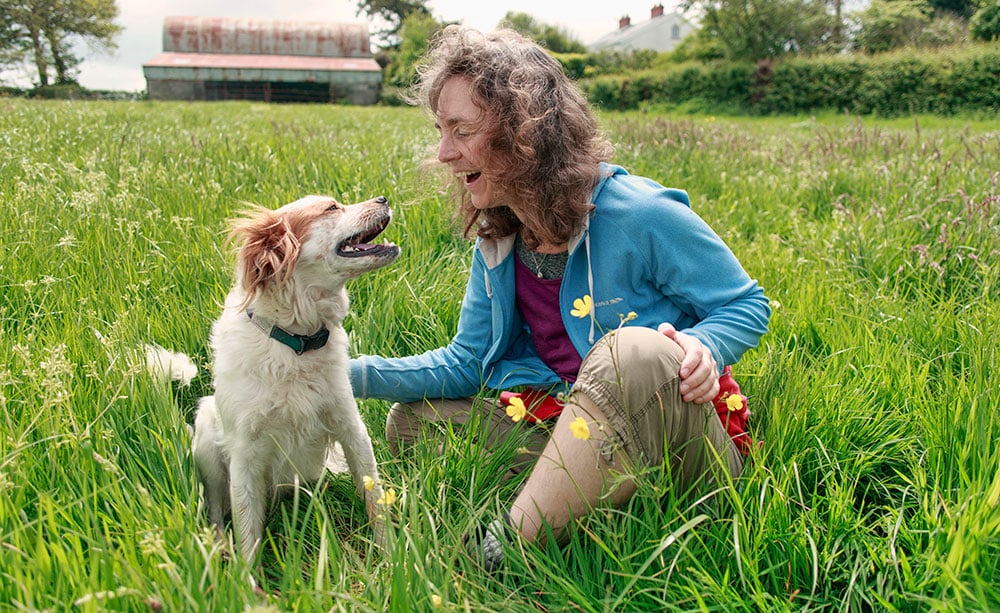 A woman playing with her dog in a grassy field